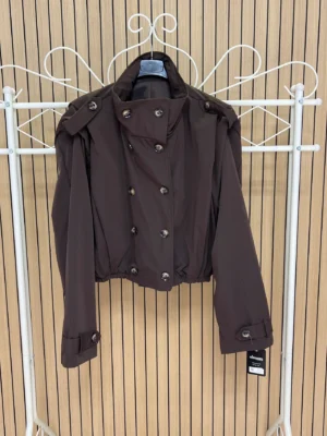 Chaqueta corta impermeable solapa hombro chocolate