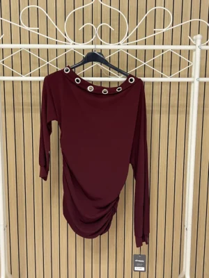 Camiseta manga larga lycra con anillas plateadas en el pecho granate
